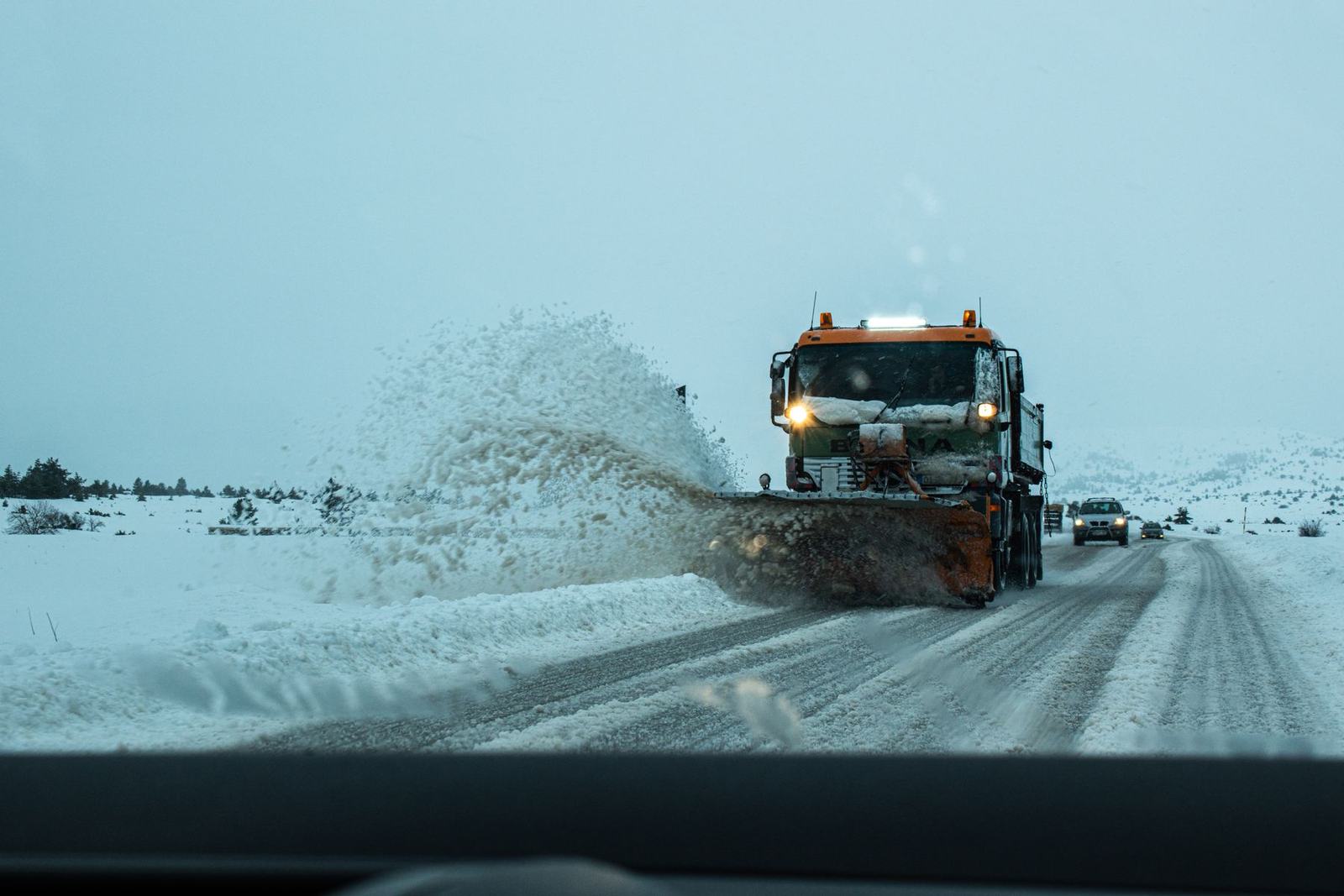 Plow truck clearing a snow-covered residential road